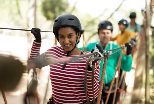 Adventure and Entertainment Insurance - Friends Wearing Helmets and Protective Great While Enjoying a Zip Line in an Adventure in Park